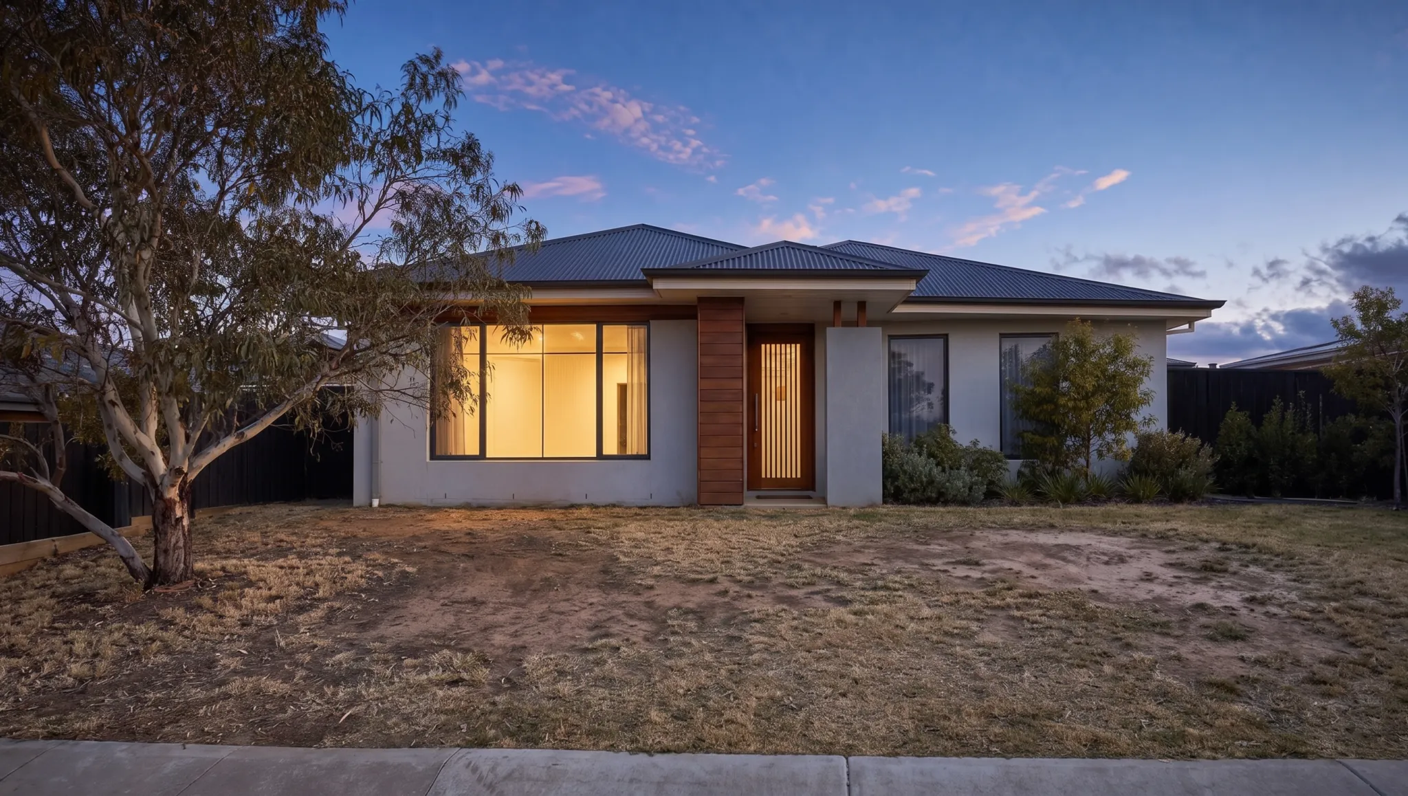 A tired Canberra backyard at dusk with dead patchy lawn, before landscaping
